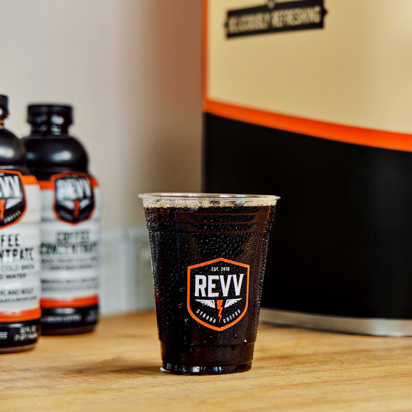 A plastic cup of REVV Cold Coffee next to bottles.