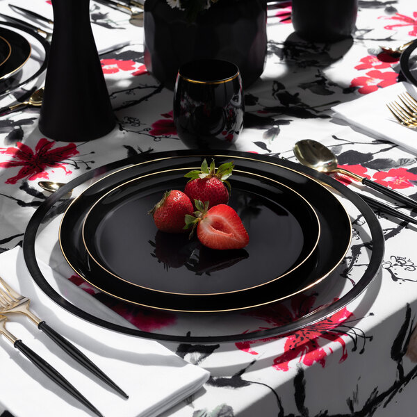 A table set with Posh Setting black plastic plates with gold bands, a fork, and a black and white cloth.