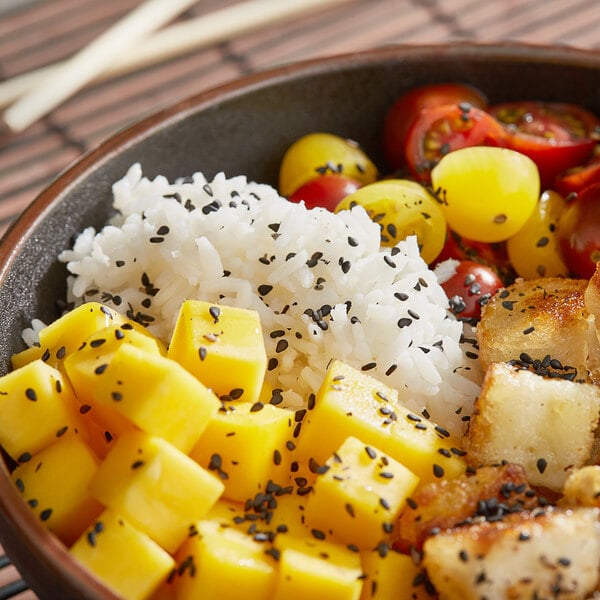 A bowl of rice and vegetables topped with black sesame seeds.