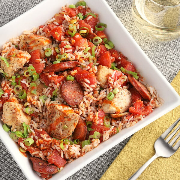 A bowl of rice with meat and vegetables seasoned with McCormick Culinary Cajun Seasoning on a yellow napkin.