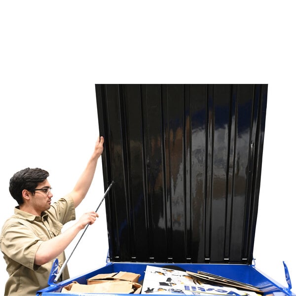 A man installing a black plastic lid on a large metal hopper.