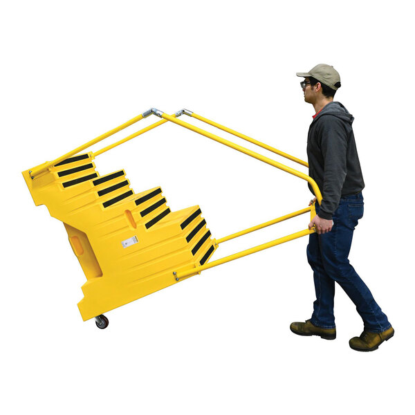A yellow polyethylene four-step step stool with handrails and casters being moved by a person.