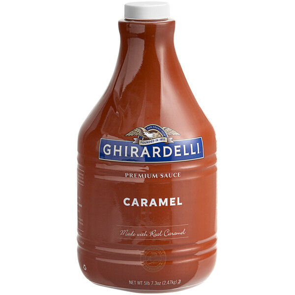 A case of 6 Ghirardelli Caramel Flavoring Sauce bottles on a grocery store shelf.