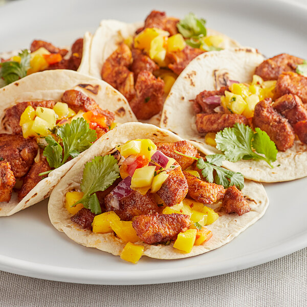 A plate of tacos with meat and vegetables topped with McCormick Culinary Ground Cayenne Pepper.