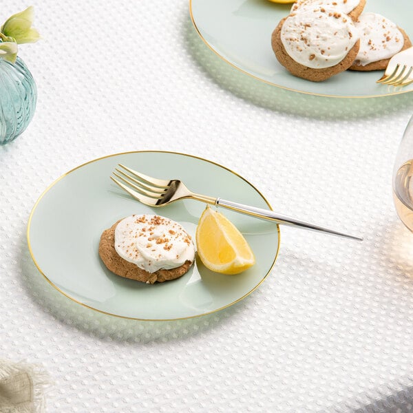 A Posh Setting turquoise plastic coupe plate with a gold band holding a cookie with white frosting and nuts next to lemon slices.