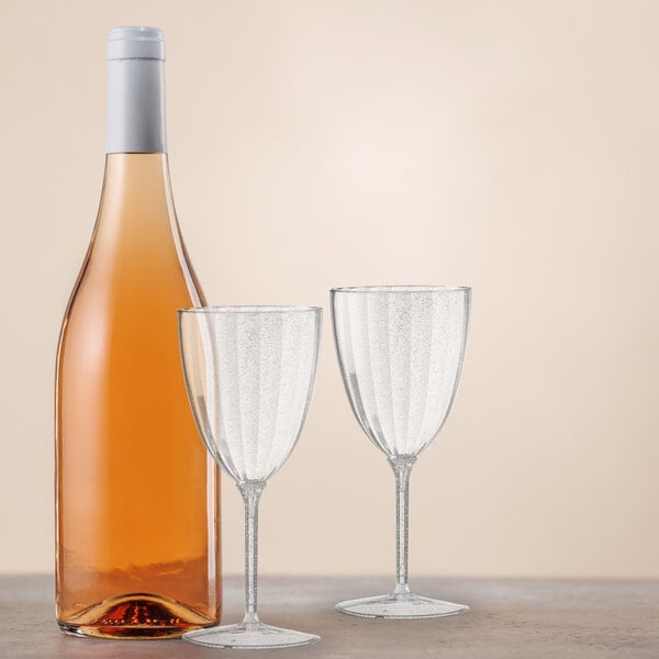 A bottle of wine and two Posh Setting silver glitter plastic wine glasses on a table.