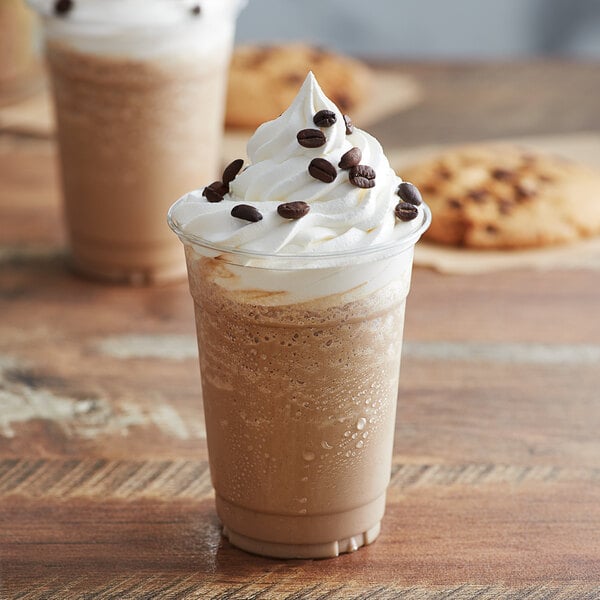 A close-up of a cup of Big Train espresso blended ice coffee with whipped cream and chocolate chips.