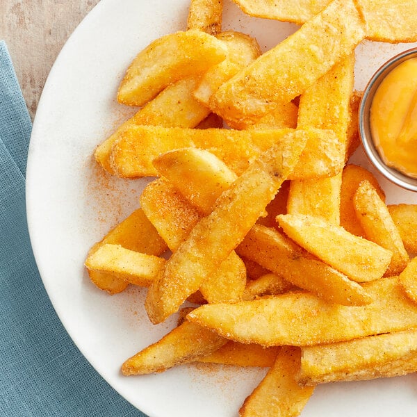 A plate of Lawry's seasoned french fries with a small bowl of sauce.