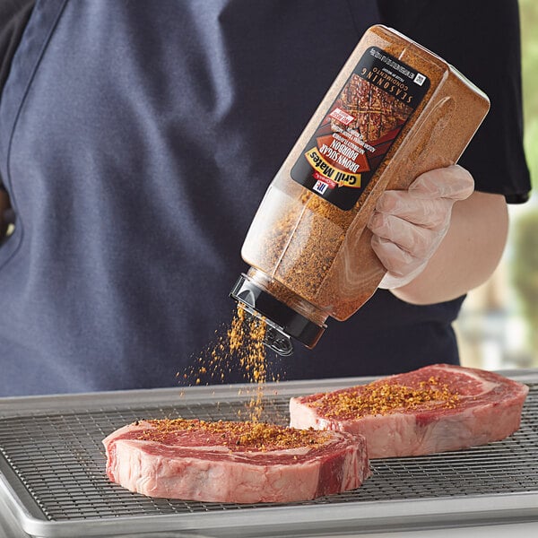 A person sprinkling McCormick Grill Mates Brown Sugar Bourbon Seasoning on a raw steak.