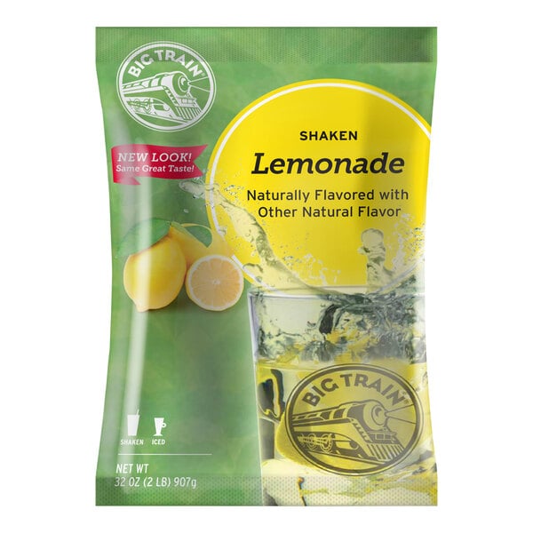 A bag of Big Train Shaken Lemonade Drink Mix on a counter with a glass of lemonade.