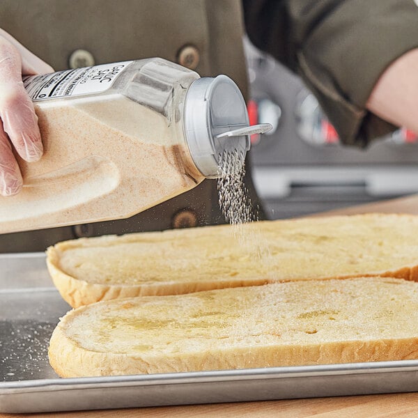 A person sprinkling McCormick Culinary Garlic Salt onto a piece of bread.