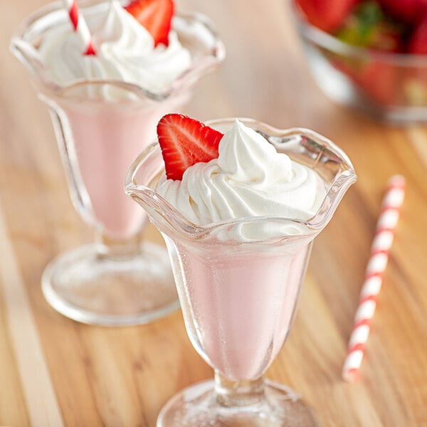 Two glasses of Big Train strawberry frappes topped with whipped cream and strawberries.