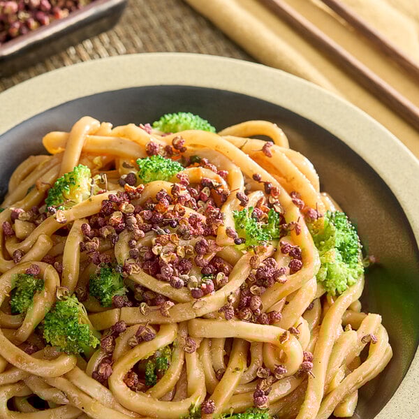 A bowl of noodles with broccoli and HUNSTY Red Sichuan Peppercorn sprinkles.