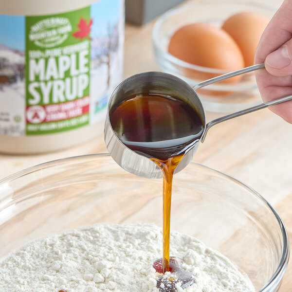 A person pouring Butternut Mountain Farm Very Dark Pure Vermont Maple Syrup into a bowl of eggs.