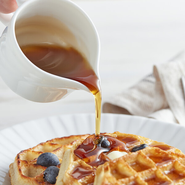 A person pouring Butternut Mountain Farm maple syrup on a waffle.