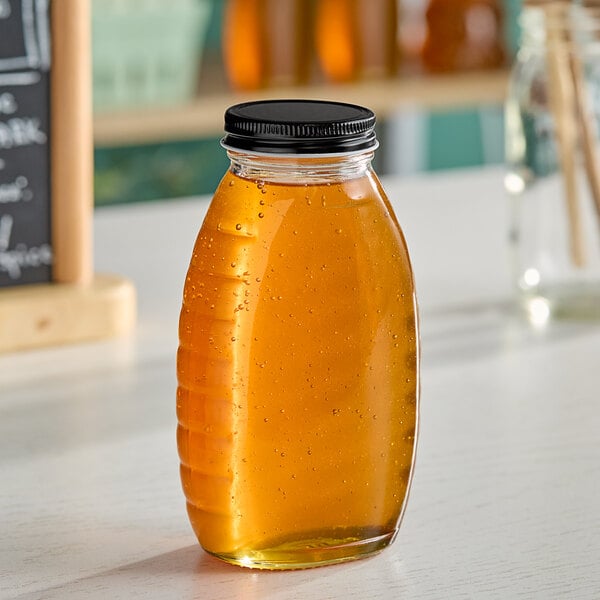 A Classic Queenline glass honey jar filled with honey on a table.