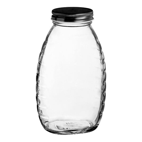A clear glass classic queenline honey jar with a black metal lid.