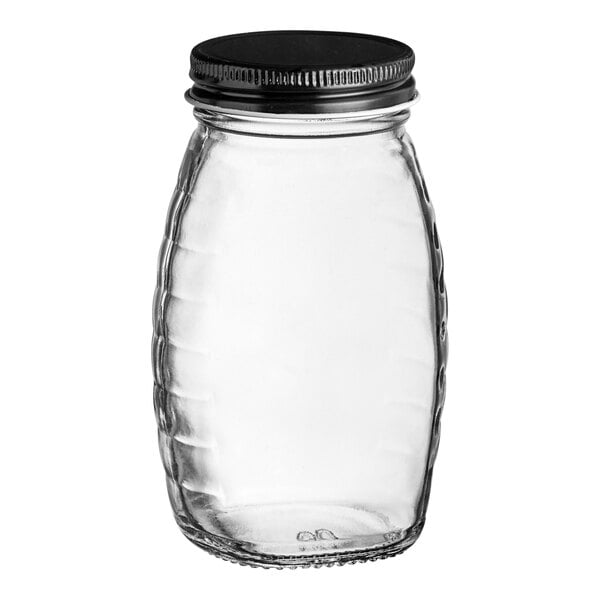 A clear glass Classic Queenline honey jar with a black metal lid.