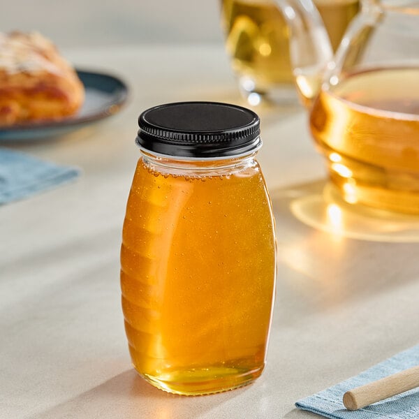 A Classic Queenline glass jar of honey on a table.