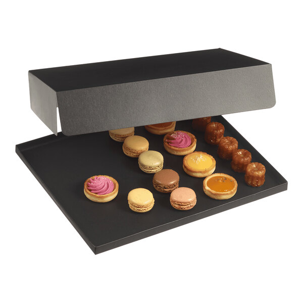 A black Solia paperboard tray with various pastries and desserts on a table.