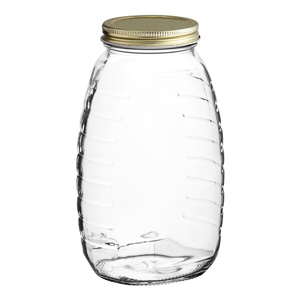 A clear glass Classic Queenline honey jar with a gold metal lid.