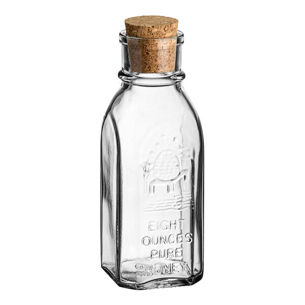 A clear glass Muth honey jar with cork lid.