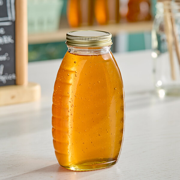 A Classic Queenline glass honey jar filled with honey on a table.