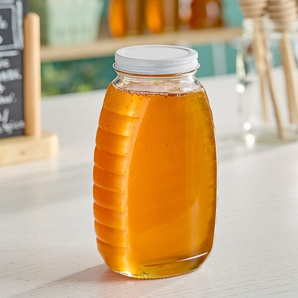 A Classic Queenline glass honey jar filled with honey on a table.