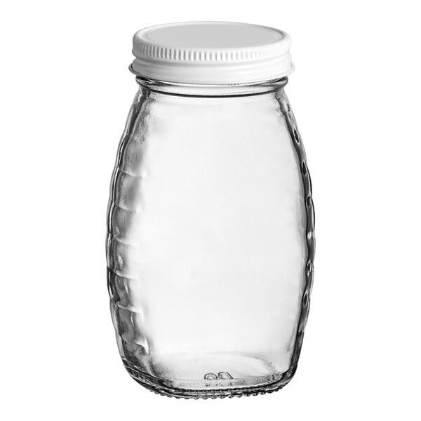 A clear glass Classic Queenline honey jar with a white metal lid.