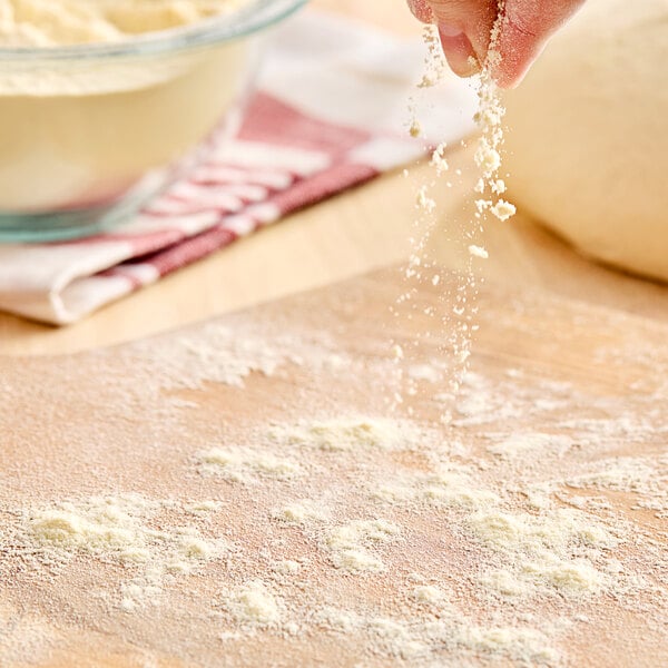 A person sprinkling Caputo Semola durum semolina flour on dough.