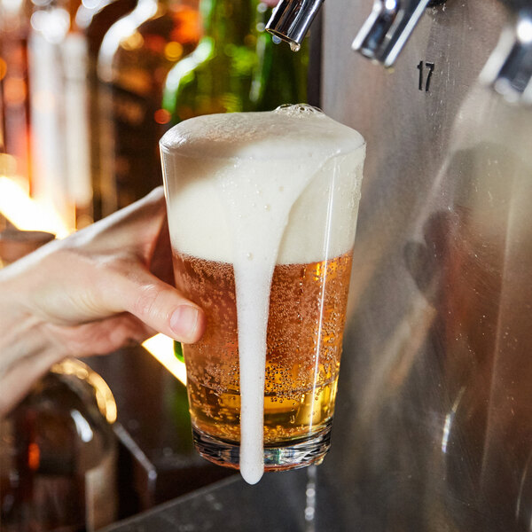 A person holding a Tossware Reserve Go-To mixing glass filled with beer.