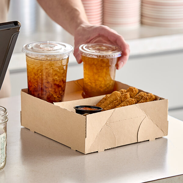 A person holding a Southern Champion drink carrier with plastic cups of brown liquid.