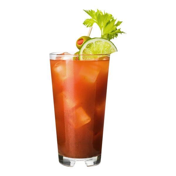 A Tossware stackable highball glass filled with orange liquid and ice with a lime garnish.