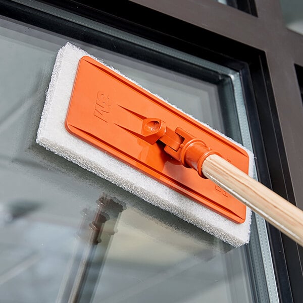 A white cleaning pad with a handle on a window.
