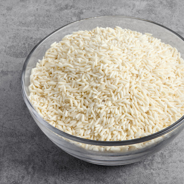A glass bowl filled with uncooked long grain sweet Thai rice.