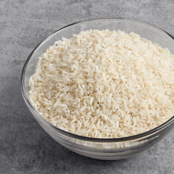 A glass bowl filled with uncooked long grain white rice.