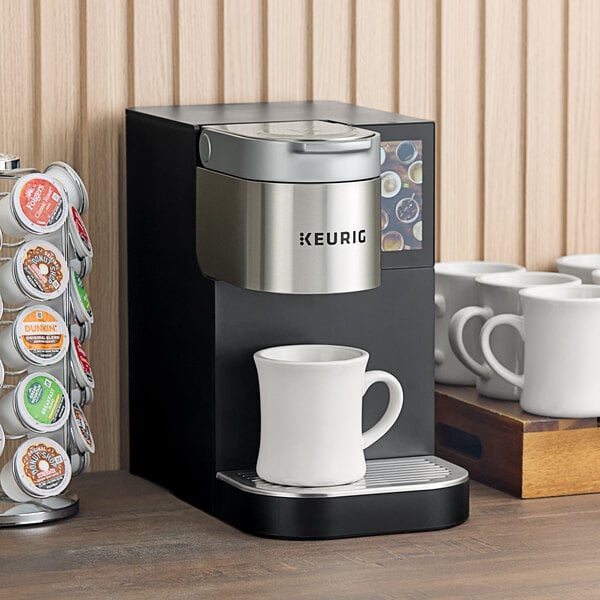 A Keurig commercial single serve coffee maker on a table with mugs.