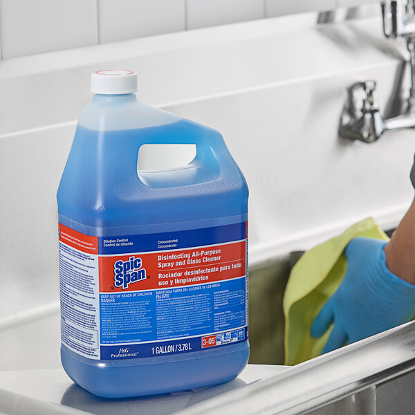 A person using Spic and Span Glass Cleaner to wash a sink.