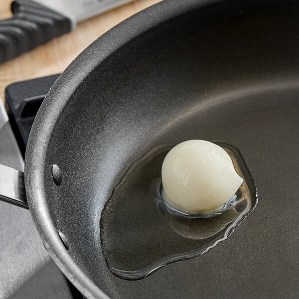 A white Butcher Boy Lard pail on a black surface with a frying pan and a white egg in it.