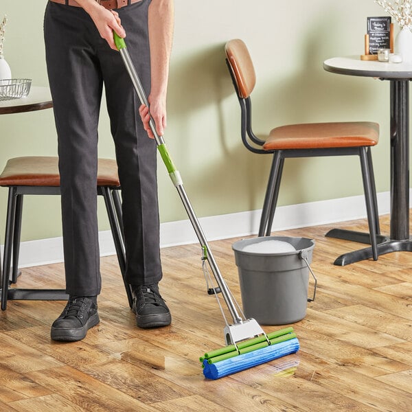 A person using a Lavex PVA mop to clean the floor in a professional kitchen.