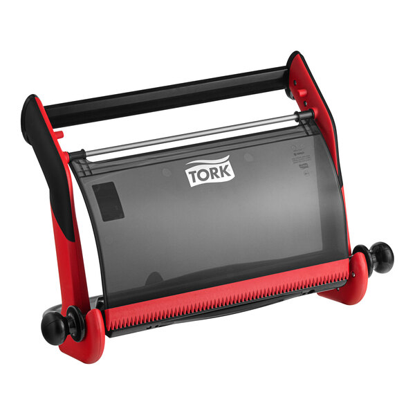 A red and black plastic Tork wall-mount wiper roll dispenser.