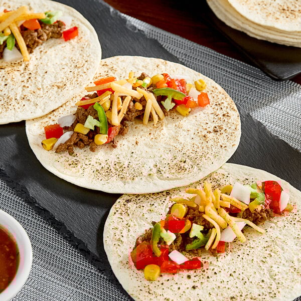 A group of El Mejor flour tortillas with meat and vegetables on them.