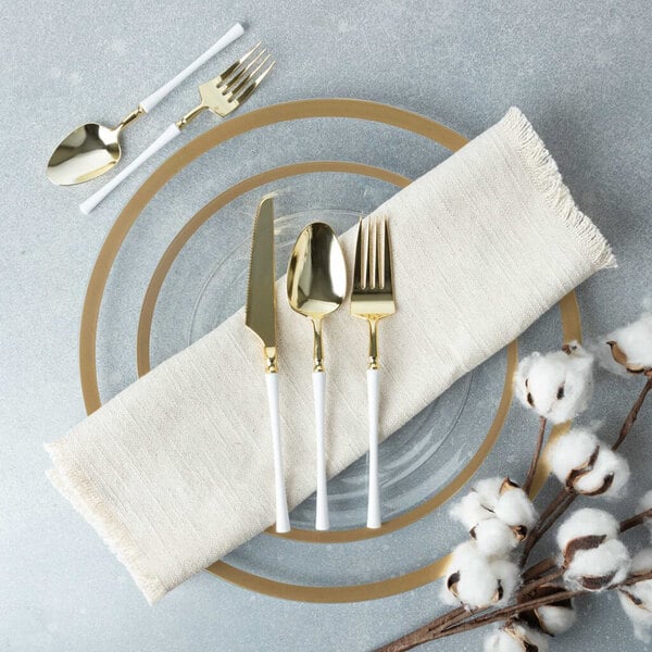 A Posh Setting gold and white plastic knife on a table next to a plate