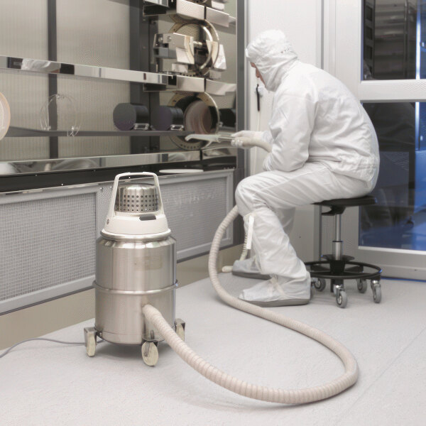 A man in white protective clothing using a Nilfisk stainless steel cleanroom canister vacuum.
