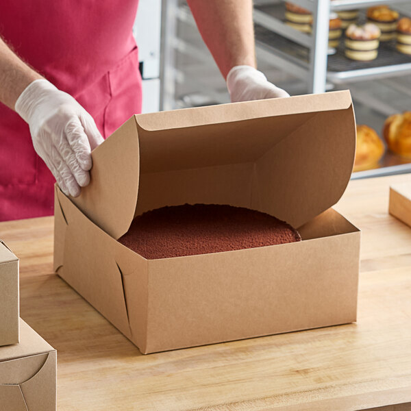 A person in gloves opening a Baker's Lane cake box.