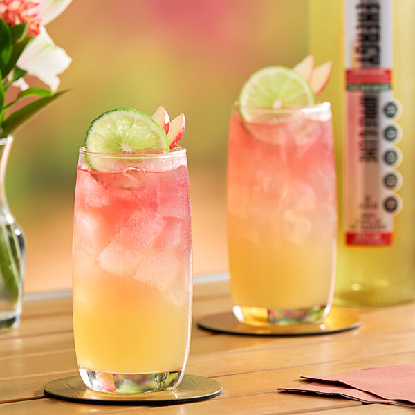 Two glasses of SHOTT Apple and Lime energy drink with lime slices on top.
