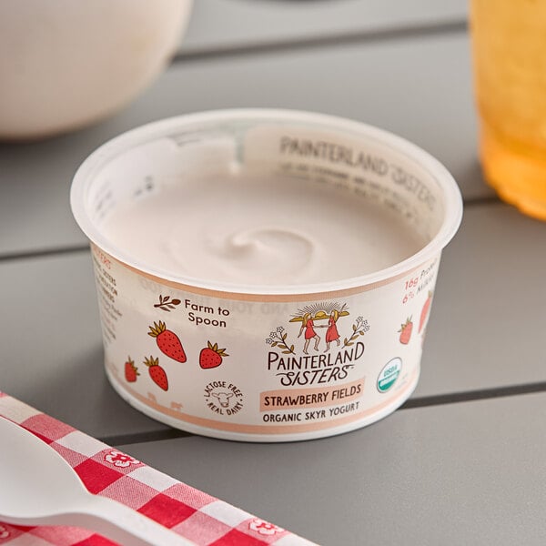 A white container of Painterland Sisters Strawberry Fields organic skyr yogurt on a table.