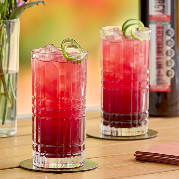 A close-up of two glasses of red SHOTT Blackcurrant and Lime energy drink with lime garnish.
