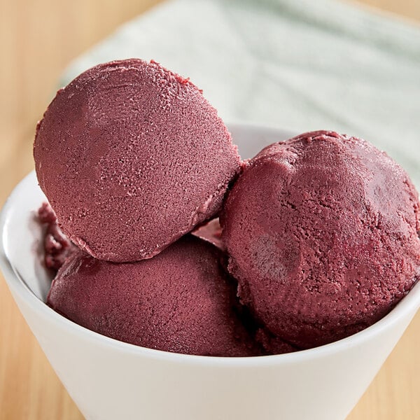 A bowl of acai ice cream with red berries on top.