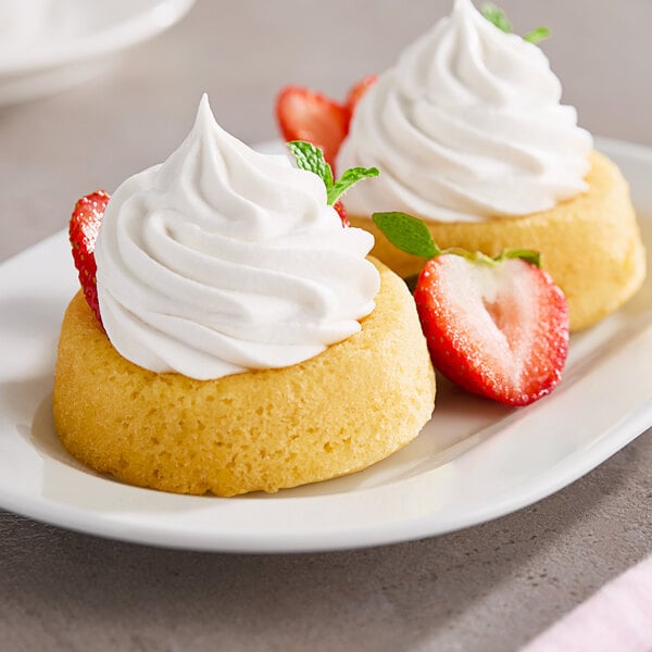Two small desserts topped with So Delicious Cocowhip and strawberries.